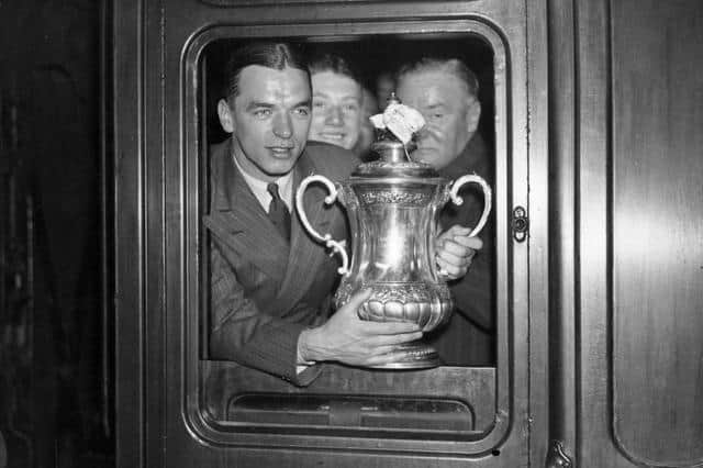 Sunderland captain Raich Carter with the FA Cup trophy out of the train window at King's Cross on May 3, 1937. Photo by J. A. Hampton/Topical Press Agency/Getty Images.