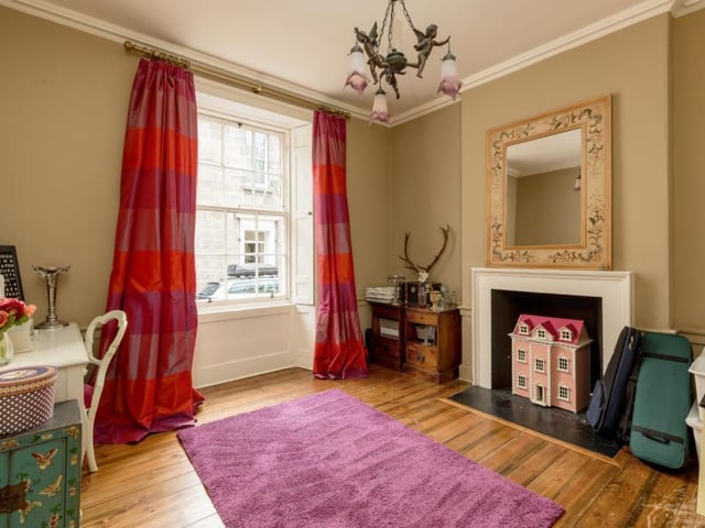 Sitting room with wooden floor, shutters and fireplace.