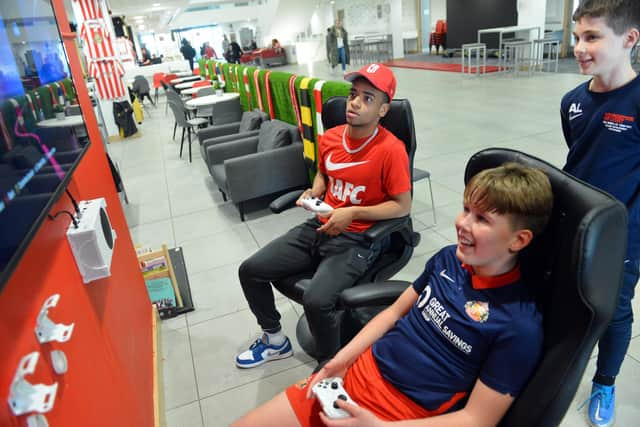 SAFC player Jewison Bennette enjoying a game of FIFA 23 against children at the Beacon of Light.