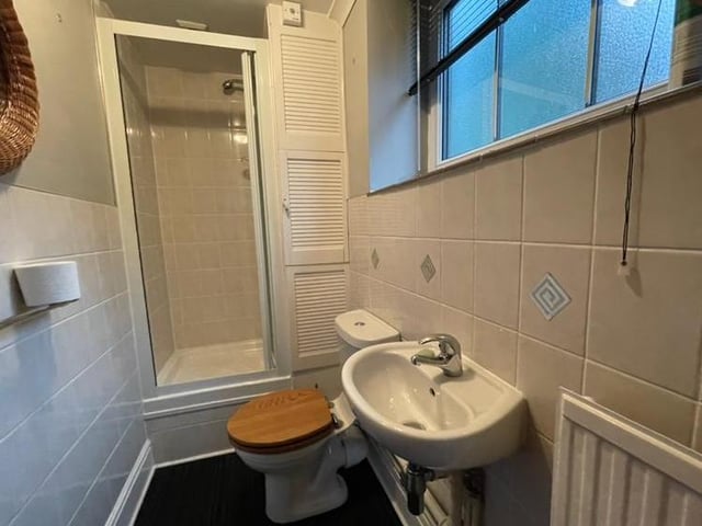 Before we head upstairs, let's take a look at this shower room, which can be found on the ground floor. It is fitted with a three-piece suite comprising a shower enclosure, low-flush WC and wash hand basin, plus tiled walls and a central heating radiator.