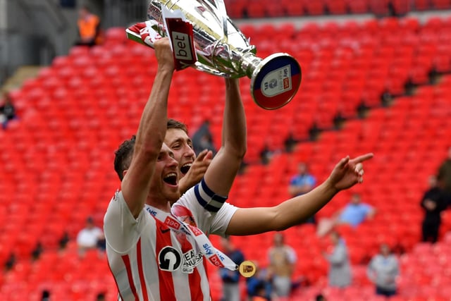 Corry Evans holds the trophy aloft
