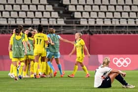 Britain's defender Steph Houghton (R) sits on the pitch watching Australia's players (L) celebrating their victory after the extra second half of the Tokyo 2020 Olympic Games women's quarter-final football match between Britain and Australia at Ibaraki Kashima Stadium in Kashima city, Ibaraki prefecture on July 30, 2021. (Photo by SHINJI AKAGI / JIJI PRESS / AFP) / Japan OUT (Photo by SHINJI AKAGI/JIJI PRESS/AFP via Getty Images)