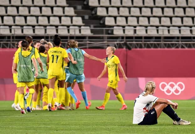 Britain's defender Steph Houghton (R) sits on the pitch watching Australia's players (L) celebrating their victory after the extra second half of the Tokyo 2020 Olympic Games women's quarter-final football match between Britain and Australia at Ibaraki Kashima Stadium in Kashima city, Ibaraki prefecture on July 30, 2021. (Photo by SHINJI AKAGI / JIJI PRESS / AFP) / Japan OUT (Photo by SHINJI AKAGI/JIJI PRESS/AFP via Getty Images)