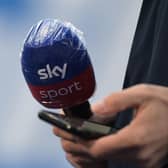 A journalist holds a microphone with the logo of the television sports channel Sky Sports and a smartphone