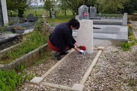 Regine places a small bunch of flowers on the grave of Private Thomson.