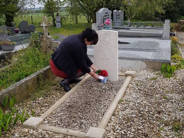 Regine places a small bunch of flowers on the grave of Private Thomson.