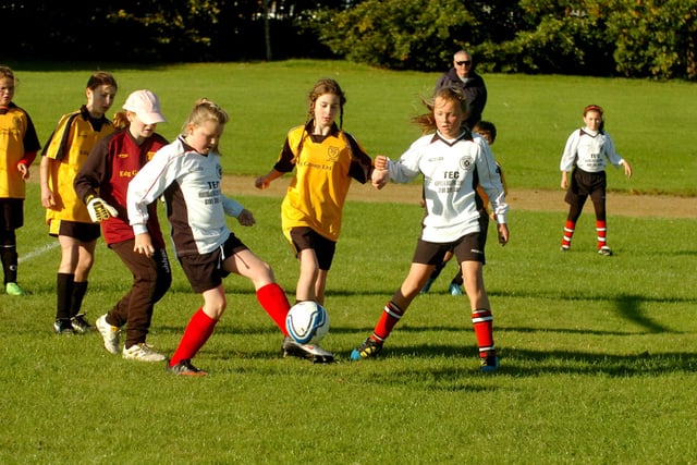 Lumley Ladies Reds under 10's in white face a fight for possession with Darlington Spraire Lasses.