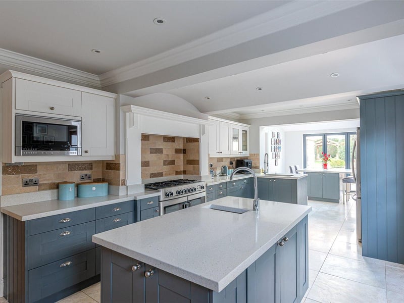 The recently appointed hand painted kitchen includes fitted cupboards and integrated appliances, with a double oven and central island, plus a seating area overlooking the garden.