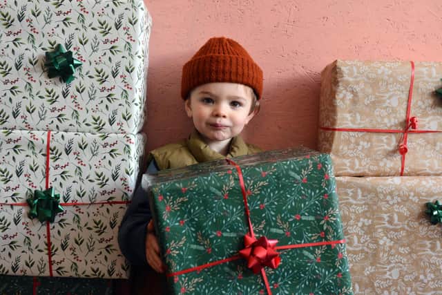 Reggie Robinson Forster, two, holding some of the gifts which have been dropped off for other children at his dad's restaurant