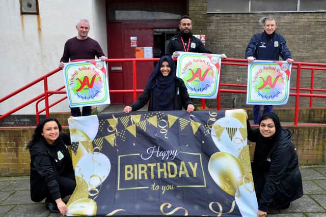 Standing on platform holding the new Young Asian Voices Logo are (left to right) Pul Brigham. Kumareswaradas Ramanathas and Dr. Paul Andrew as fellow group members (left to right) Shahzana Aslam, Mahnur Roushan and Rufsana Begum hold the groups 25th birthday banner. Picture by FRANK REID