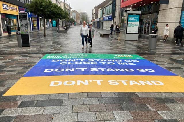 Signs, including this one on the ground in High Street West, have been put in place to remind people to keep their distance while out shopping.