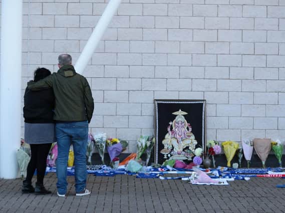 People pay tribute at Leicester City Foootbal Club after a helicopter used by club owner Vichai Srivaddhanaprabha, crashed into flames in a car park near the stadium shortly after 8.30pm on Saturday. Picture Aaron Chown/PA Wire