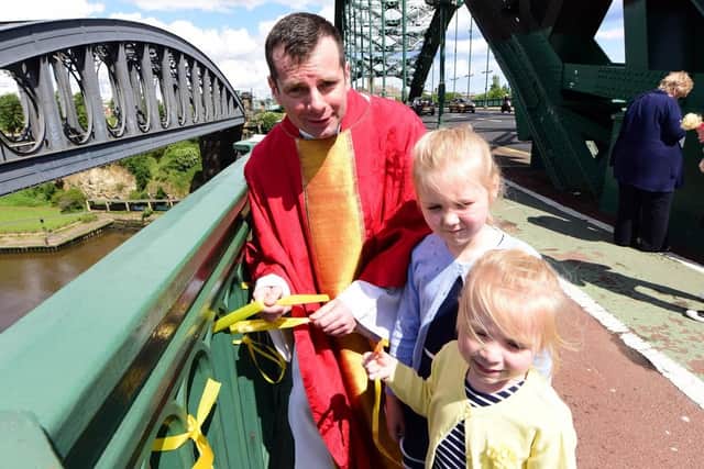 Fr Marc Lyden-Smith with Nancy (7) and Harriett (4) Corr, tying yellow ribbons to Wearmouth Bridge to raise awareness of Cystic Fibrosis.