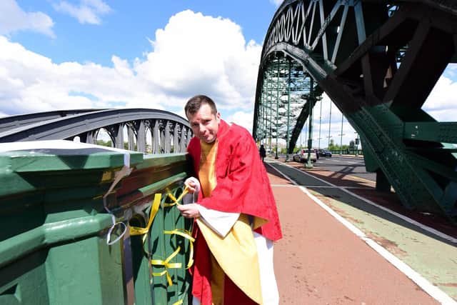 Fr Marc Lyden-Smith ties yellow ribbons to Wearmouth Bridge to raise awareness of Cystic Fibrosis.