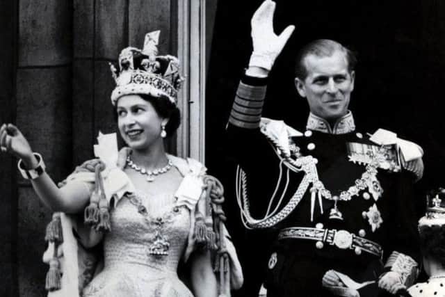 Queen Elizabeth II wearing the Imperial State Crown, and the Duke of Edinburgh, in the uniform of Admiral of the Fleet, waving from the balcony of Buckingham Palace after the Queen's Coronation. Photo: PA Wire