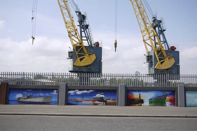 A line-up of painted ships under the cranes.
