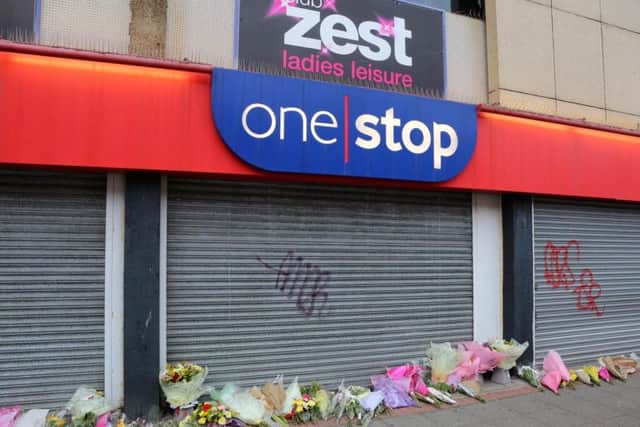 Floral tributes left outside of the One Stop shop where Joan Hoggett worked.