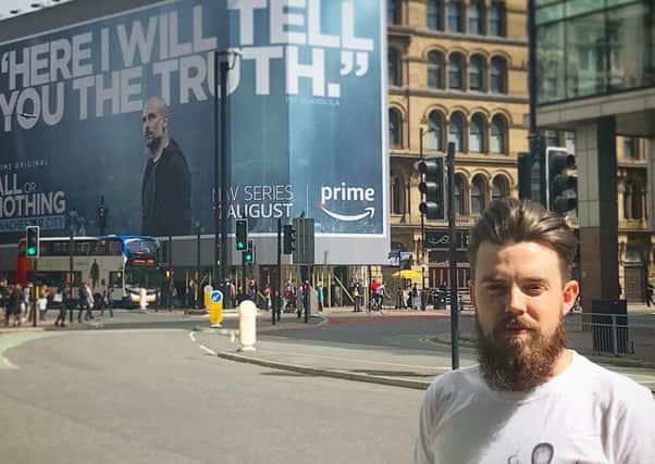Jonathan Smith in front of a billboard advertising the TV series.