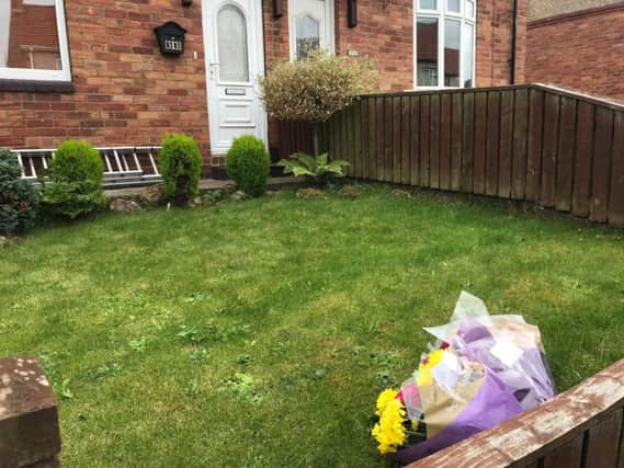 Floral tributes have been left outside the home where the bodies of a man and a woman were found
