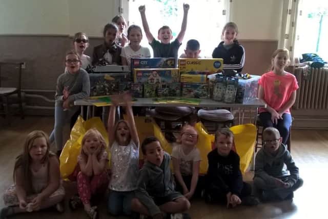 Blake Simpson, back row with arms up, and other children with the delivery of Lego.