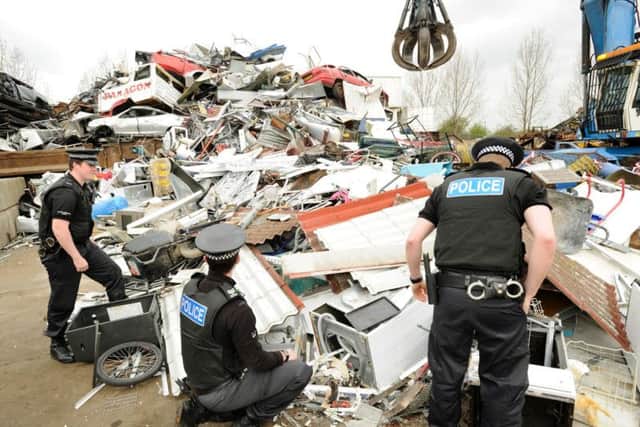 Police officers search a scrapyard for evidence of stolen metal.