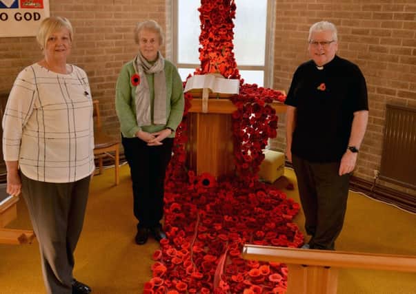 Judith Monaghan, Hilary Brereton and Reverend Alf Wood alongside the cascade of crocheted poppies at Houghton Methodist Church.
