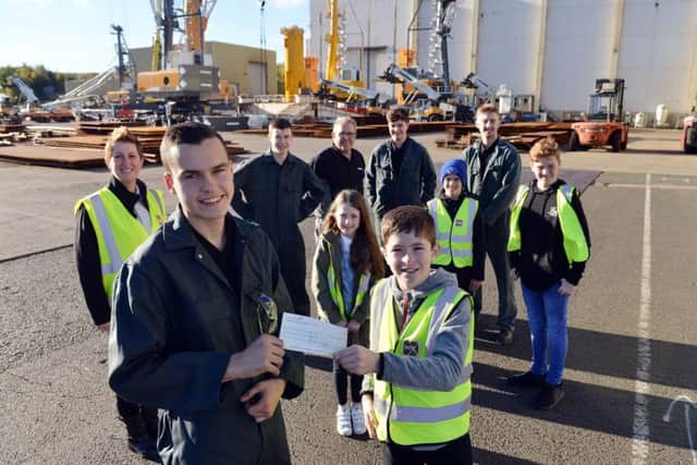 Nathan Haley (front left) apprentice at Liebherr presents a cheque for Â£834 to Bradley Ford Stubbs from the Box Youth Project.