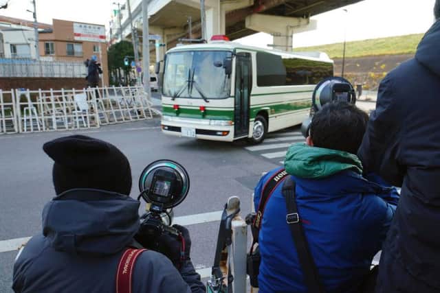 Photographers film a vehicle presumably carrying former Nissan chairman Carlos Ghosn entering Tokyo Detention Center. Picture: AP Photo/Eugene Hoshiko.