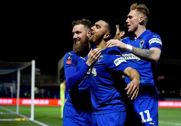 AFC Wimbledon's Scott Wagstaff celebrates scoring his side's third goal of the game against West Ham with team-mate Kwesi Appiah (centre).