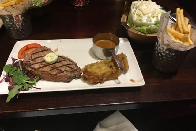 Sirloin steak with peppercorn sauce, wedge of lettuce with garlic and cheese dressing and portion of fries.
