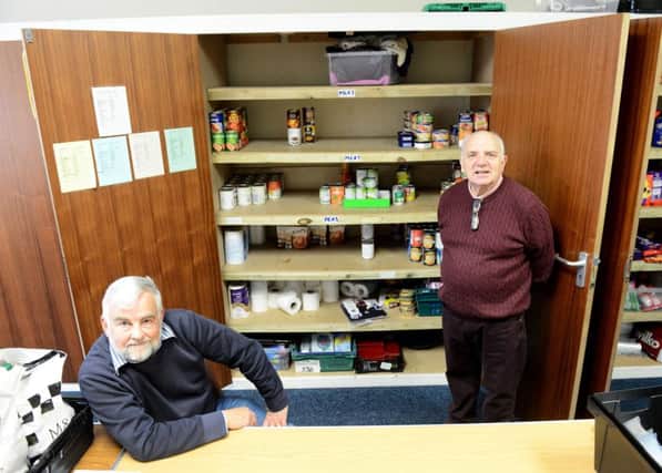 Granville Hawkins (right) with Elim Church Foodbank volunteer Dave Smith in front of a near empty food cupboard after this week's foodbank