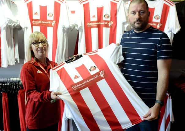 Sunderland AFC retail assistant Tracy Cowling hands Sunderland supporter Lee Halliday his new Sunderland shirt