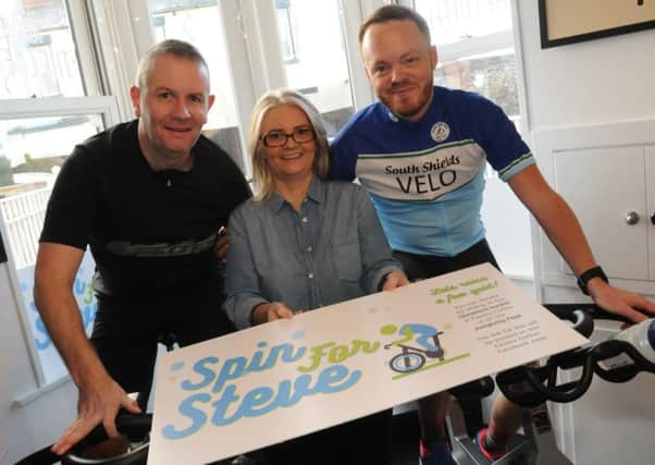 Steve Willey's wife Paula, centre, supports cyclists Scott Clark, left, and Chris Willey, during a fundraising spin at Fausto Coffee Shop.