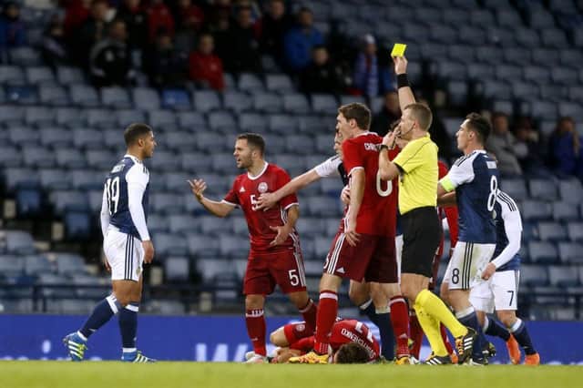 Scotland's Liam Bridcutt (left) is shown the yellow card after fouling Denmark's Erik Sviatchenko (floor) who is left injured by the challenge during an International Friendly at Hampden Park.