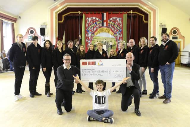 Billy Elliot writer Lee Hall and the company of the musical, including Haydn May, one of the youngsters to play Billy,  present a cheque for Â£59,438 to Malcolm Fallow, Chief Executive Officer of the East Durham Trust at Easington Social Welfare Centre