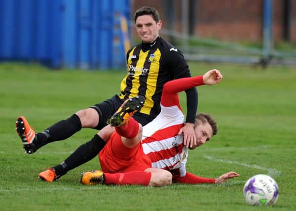 Ryhope CW striker Conor Winter (red and white) is the fall guy in this challenge at Hebburn Town on Saturday. Picture by Tim Richardson