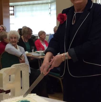 Kepier WI president Marian Furgeson cuts the birthday cake to celebrate the institute's 21st anniversary as well as the Queen's 90th birthday.