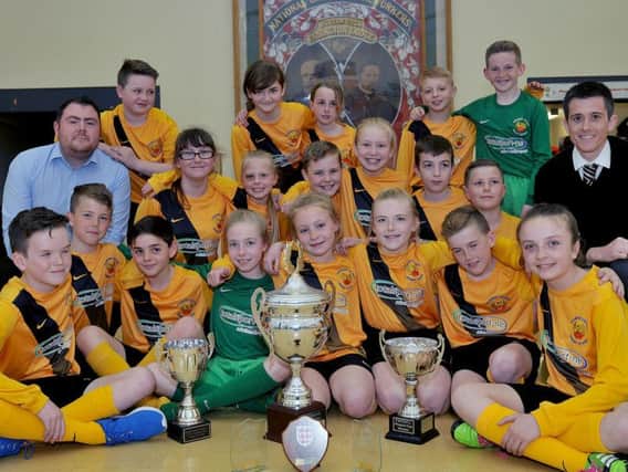 Easington Primary School boy and girl football teams and teachers Michael Shaw  (left) and Gary Adey, with the trophies they won on the way to their finals.