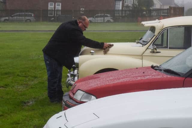 Trying to keep his pride & joy dry in Sundays adverse weather conditions is this exhibitor at the Sunderland & District Classic Vehicle Society annual show at Seaburn.