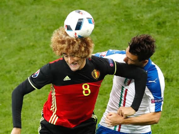 Fellainis new hair attacks the ball while he ponders his next move. Pic: PA.