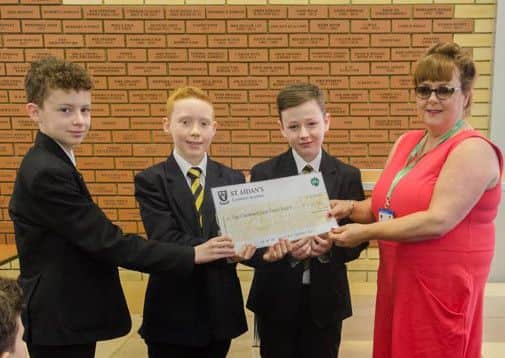 St Aidan's pupils, Jacob  Hewitt, Matthew Rich and Alex Barnes, hand over a cheque to Deborah Spraggon from Macmillan Sunderland.