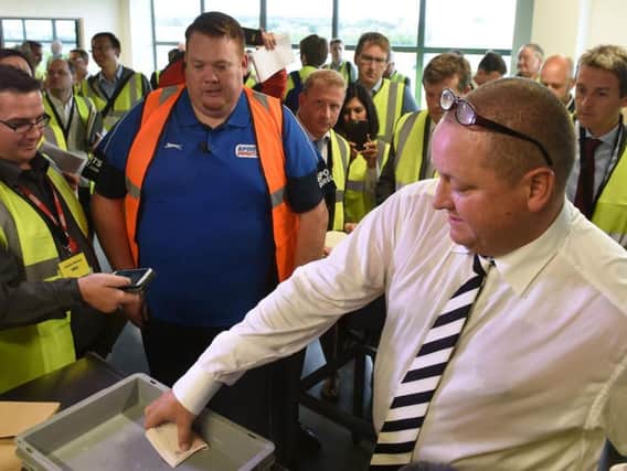 Mike Ashley pulls out a wad of 50 notes during a factory visit.