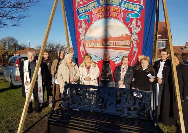 Members of the Ryhope community gather under the colliery's banner and beside the new bench.