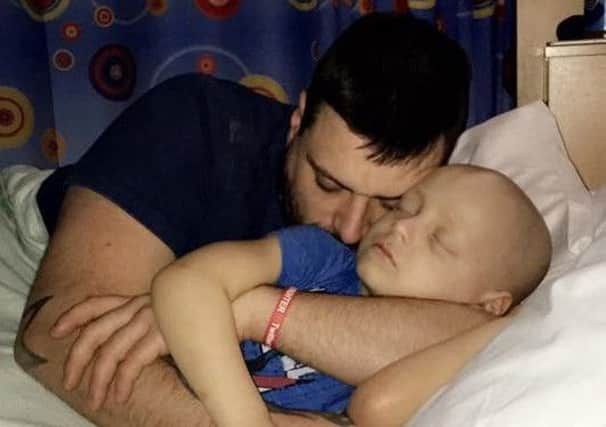 Bradley is given cuddles in his hospital bed by dad Karl.