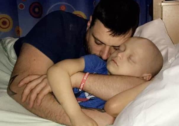 Bradley is given cuddles in his hospital bed by dad Carl.
