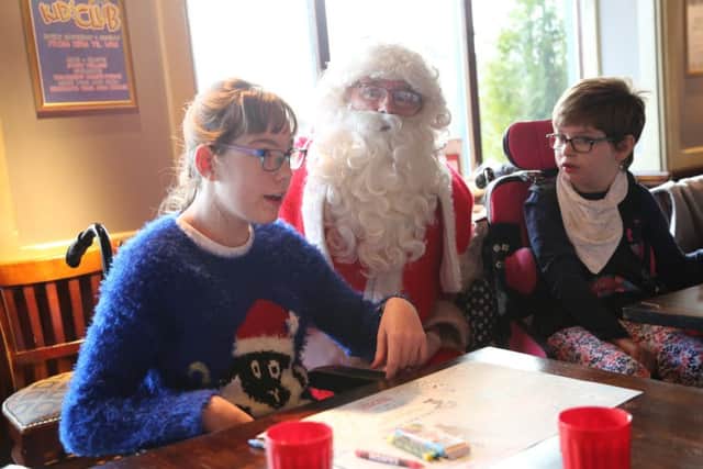 Santa speaks to Jasmine Ather and Katie Cruddas at the Grace House Christmas party in Libert Browns, Sunderland. Picture: TOM BANKS