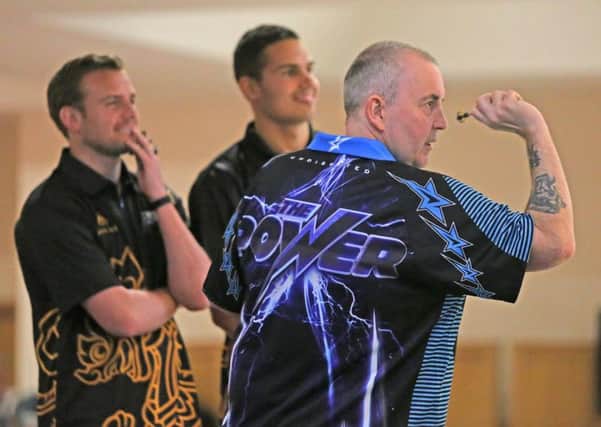 Phil Taylor plays a leg of darts with Sunderland players Lee Cattermole and Jack Rodwell.