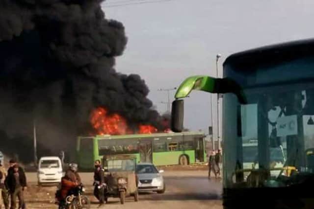 In this photo released by the Syrian official news agency SANA, smoke rises in green government buses, in Idlib province, Syria.