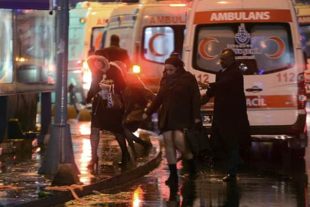 People leave as medics and security officials work at the scene after an attack at a popular nightclub in the Turkish city of Istanbul