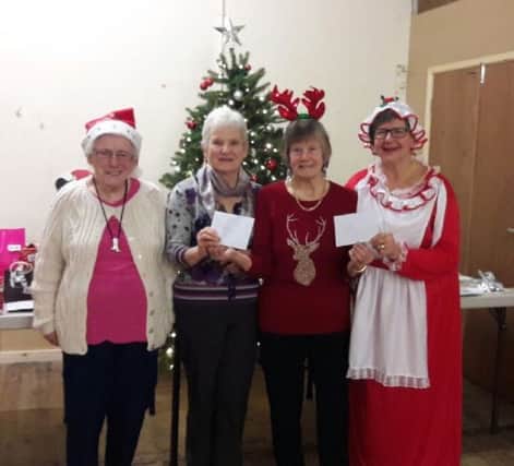 Vi Watkins from the Monday Group presents cheques to Carole Croucher on behalf of RNLI and Dorothy Allison and Alice Dixon on behalf of the Barnes Institute.